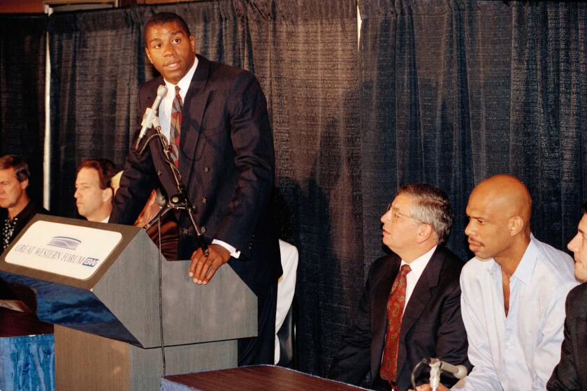 FILE - Earvin "Magic ' Johnson speaks during a press conference to announce his retirement from Los Angeles Lakers while former teammate Kareem Abdul Jabbar, right, and NBA Commissioner David Stern, looks on Nov. 7, 1991, in Inglewood, Calif. Johnson stunned the NBA and those watching his news conference live on TV by announcing he had tested positive for HIV and would be retiring from the Los Angeles Lakers. (AP Photo / Mark J. Terrill, File)