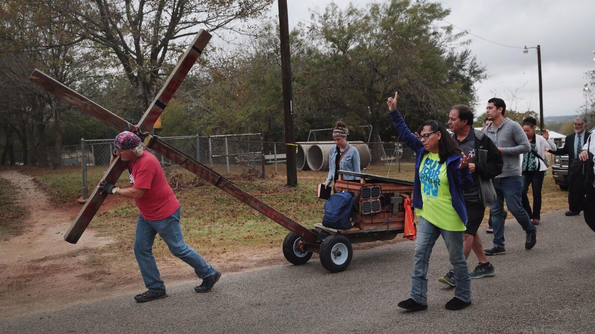 Stephen Hope pulls a cross through town followed by other worshipers after leaving Sunday service at the temporary First Baptist Church of Sutherland Springs on Nov. 12, 2017, in Sutherland Springs, Texas.