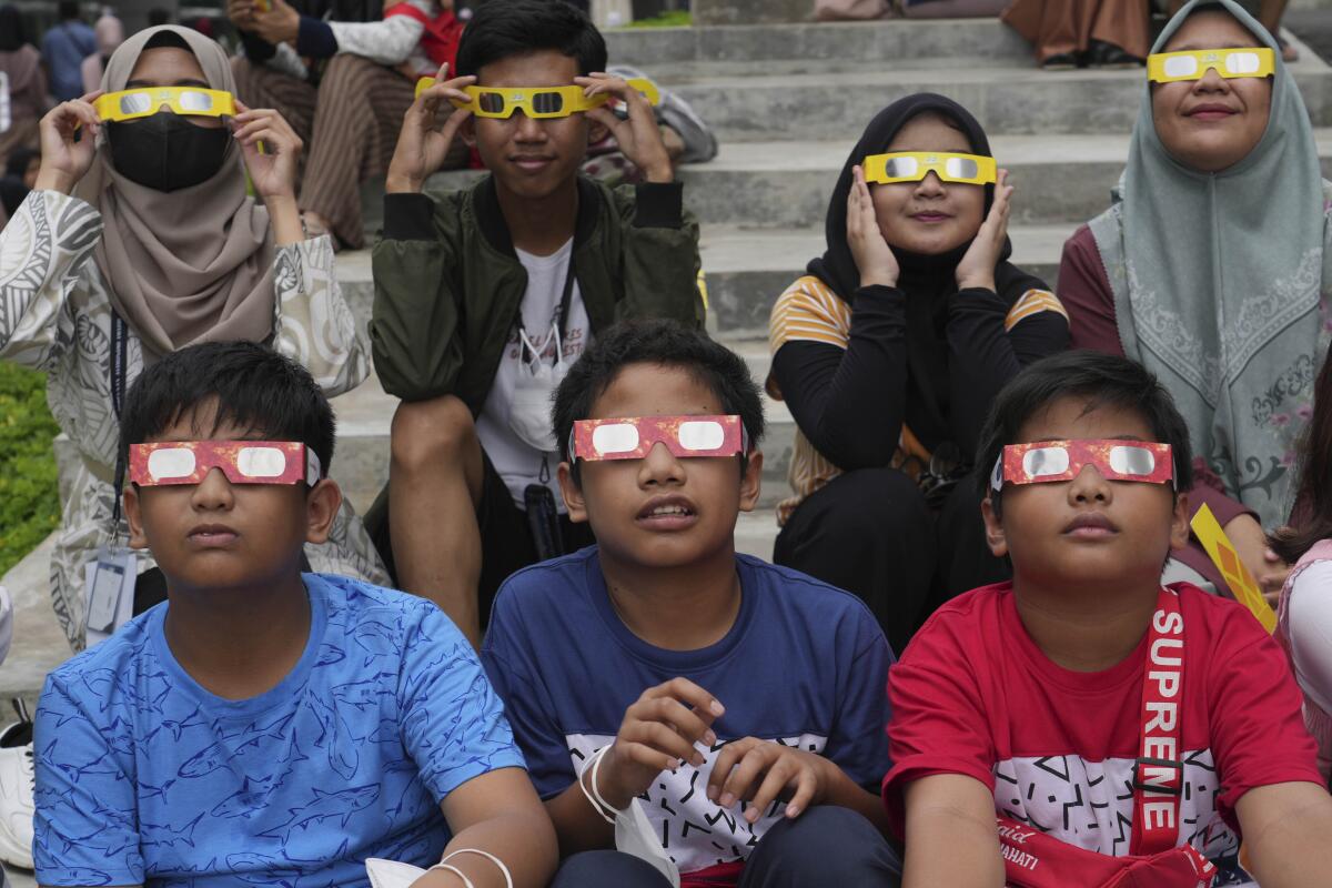 Children wear protective eclipse glasses.