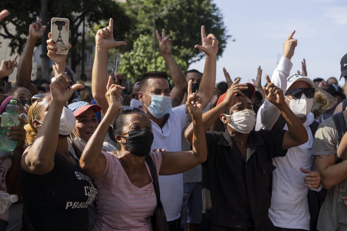 Anti-government protesters hold their arms in the air as they march in Havana on Sunday.