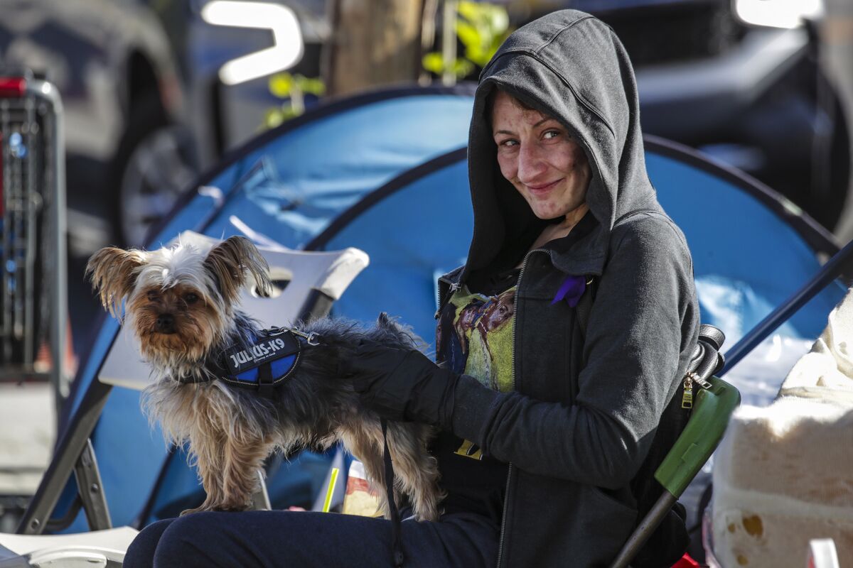 Sarah Perry and her dog Squeaker sit in a chair outside .