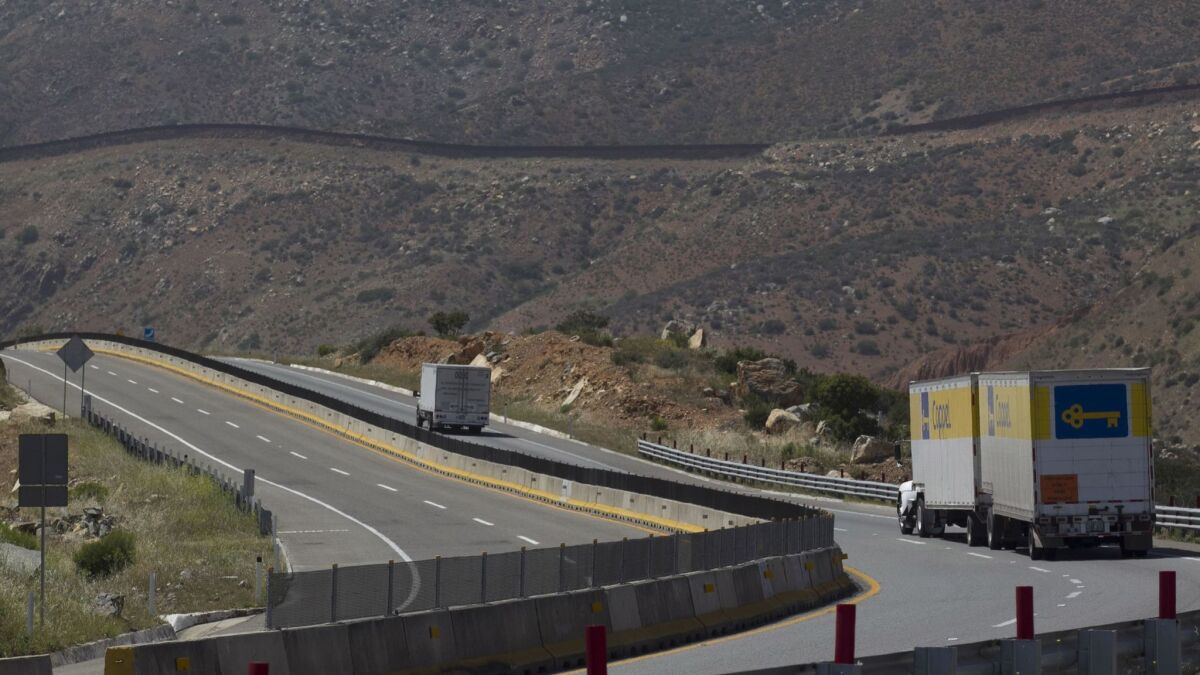 Traffic moves along Baja California's Highway 2 toll road between Otay and Tecate. The international border fence is visible in the background.