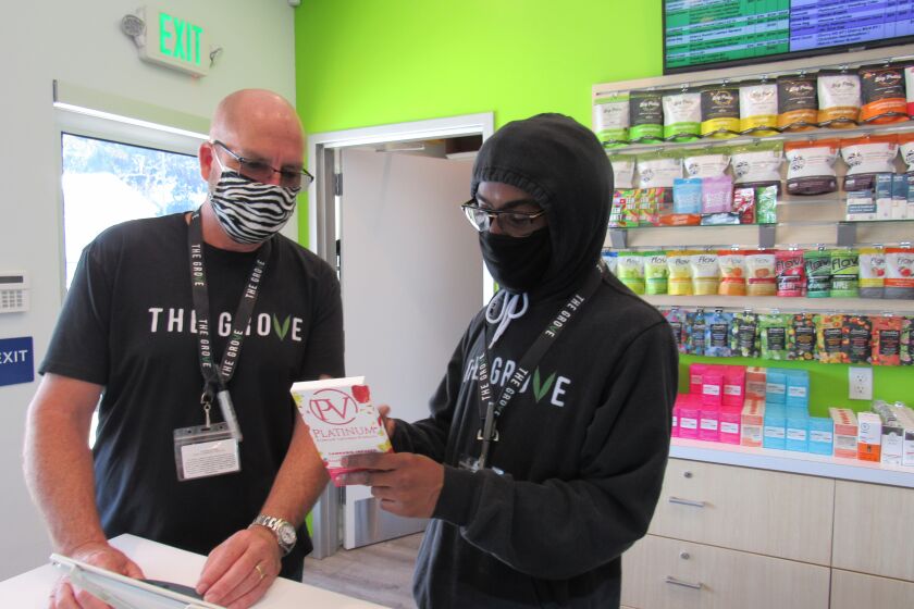 Sean McDermott (left), owner of The Grove cannabis shop in La Mesa, looks over one of the store's products with Larry Fennell, one of his first hires from the summer of 2018. The site on Center Street was the first in East County authorized by California to sell adult-use cannabis products. McDermott said he received confirmation from the state by mail on May 6 and The Grove had its first recreational cannabis product sale on May 7.