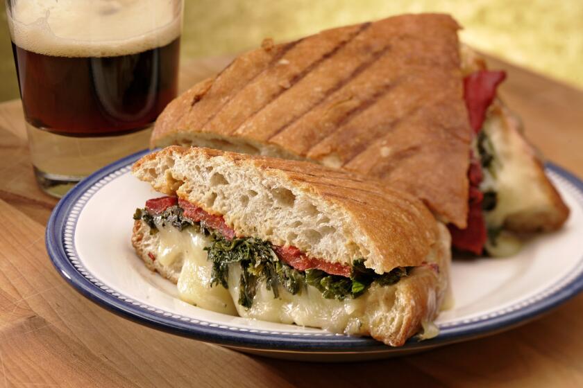 Ciabatta bread is piled with mustard greens, cheese and roasted red peppers. Recipe: Green panini with roasted peppers and Gruyere cheese