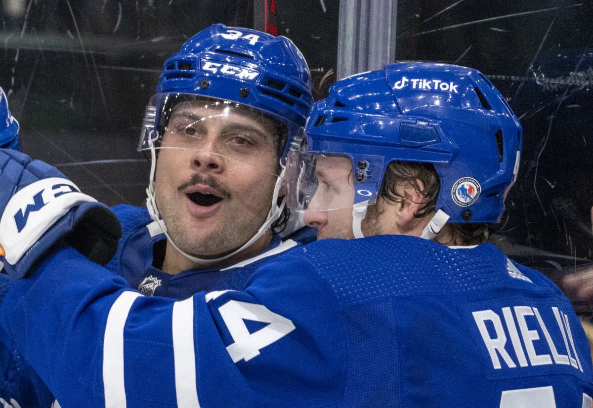 Toronto Maple Leafs centre Auston Matthews (34) celebrates his game winning goal with teammate Morgan Rielly (44) during overtime against the Calgary Flames in an NHL hockey game in Toronto on Friday, Nov. 12, 2021. (Frank Gunn/The Canadian Press via AP)