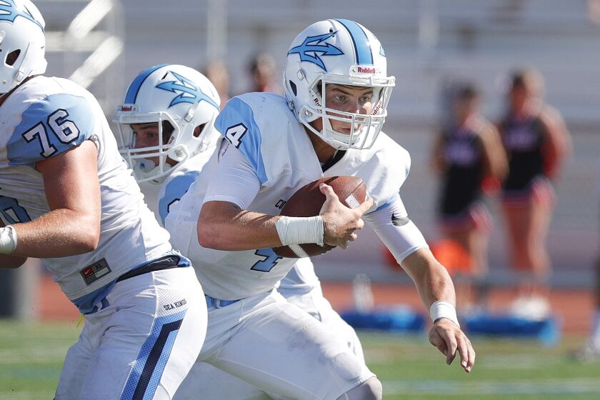 Corona del Mar's quarterback Ethan Garbers carries the ball through the Palos Verdes defensive rush to start to run before passing for a touchdown in a non-league football game on Palos Verdes High School on Friday, September 6, 2019.