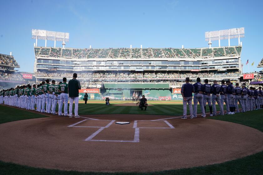 The Oakland Athletics and the Tampa Bay Rays stand during the national anthem prior to the American League wild-card game Oct. 2 at RingCentral Coliseum.