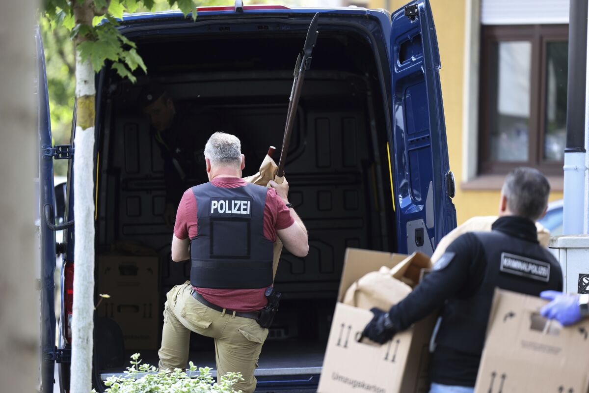 Police officers carry objects, including several stabbing weapons and spears, from the suspect's home in Essen, Germany, Thursday, May 12, 2022. Police in the western German city of Essen seized weapons from the apartment of a 16-year-old student allegedly plotting an attack on a local school. Local police said Thursday that officers searched the suspect’s apartment overnight and found spears and other sharp weapons. (David Young/dpa via AP)