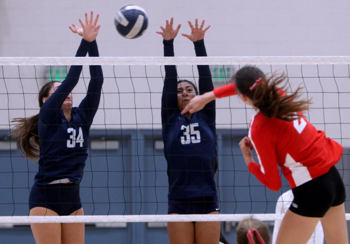 Crescenta Valley High School volleyball players Emma Glaza, left, and Jamie Santos, center, block the shot by Lydia Grote, right, in home game vs. Burroughs High School, in La Crescenta on Thursday, Sept. 12, 2019.