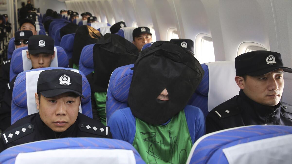 China's Xinhua News Agency released this photo that it said shows Chinese and Taiwanese wire fraud suspects, their heads covered by hoods, arriving at the Beijing airport under police guard after they were extradited from Kenya on April 13, 2016.