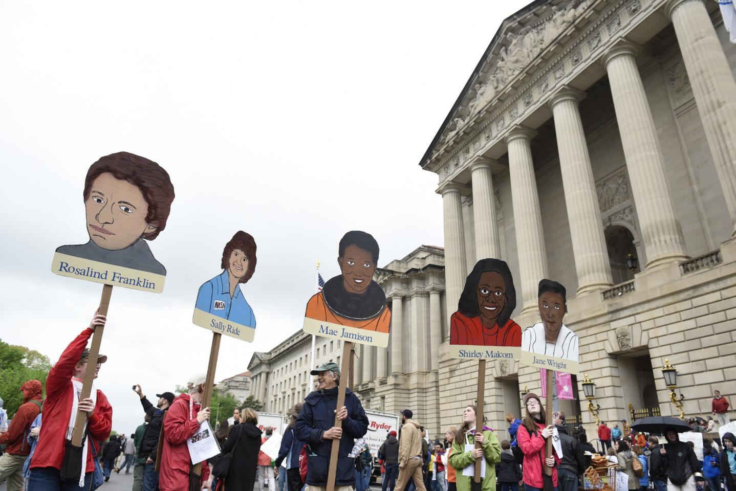 People hold signs of poineering women in science in front the U.S. Environmental Protection Agency during the March for Science in Washington, Saturday, April 22, 2017.