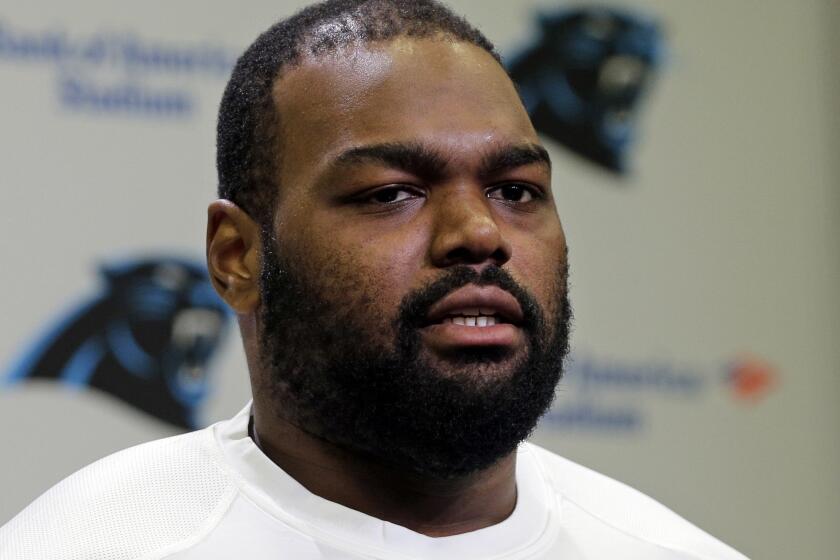 Football player Michael Oher poses in a white Carolina Panthers t-shirt