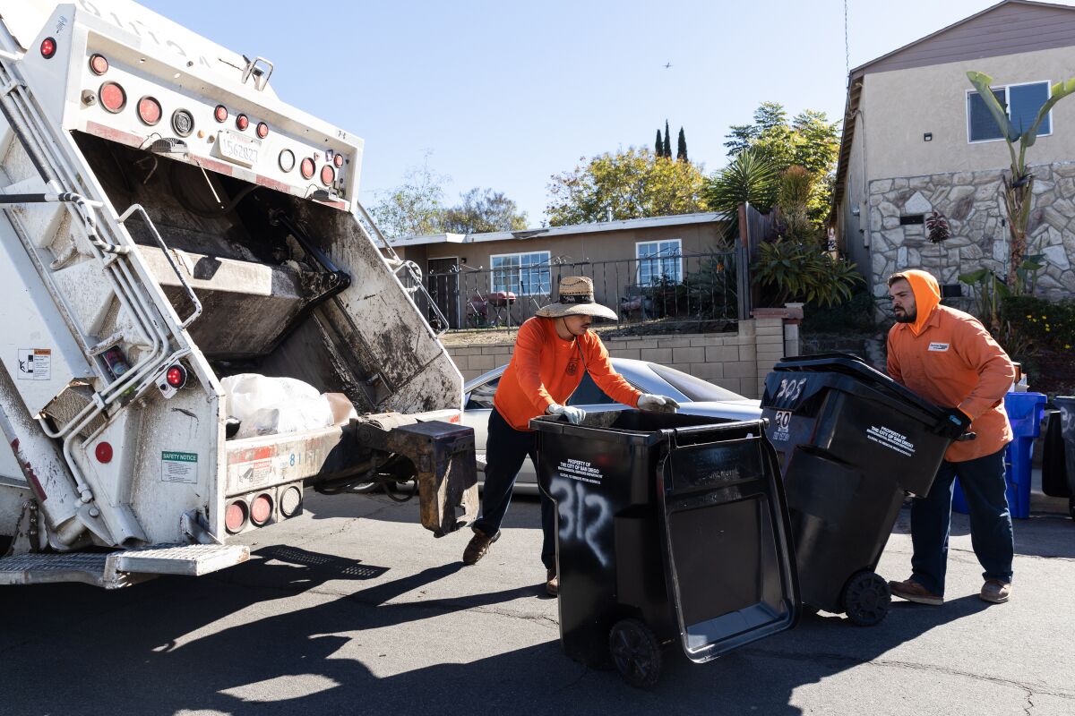 Refuse packers Andrew Ruvalcaba and Julian Trujillo load waste onto a garbage truck in Encanto.