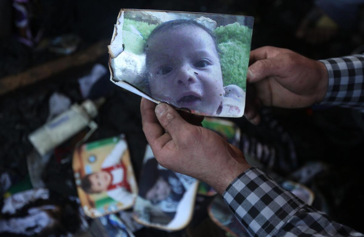 A file picture taken on July 31, 2015, shows a man holding a picture of 18-month-old Ali Dawabsha, who died when his family's house was set on fire in the West Bank village of Duma.