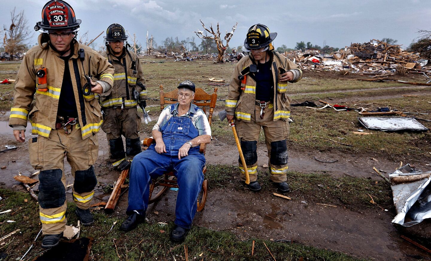 Oklahoma City firefighters check on Gene Tripp as he sits in a rocking chair where his home stood before it was destroyed by a tornado.