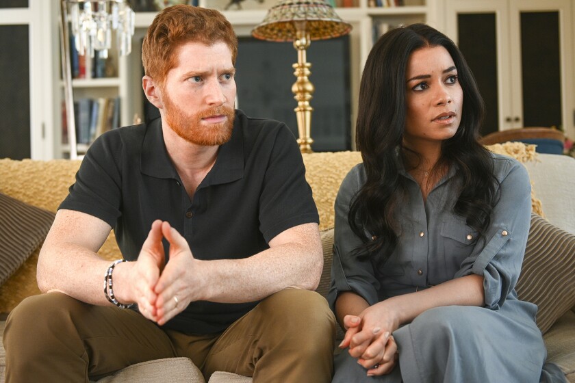 A man, left, and a woman sit side by side on a couch