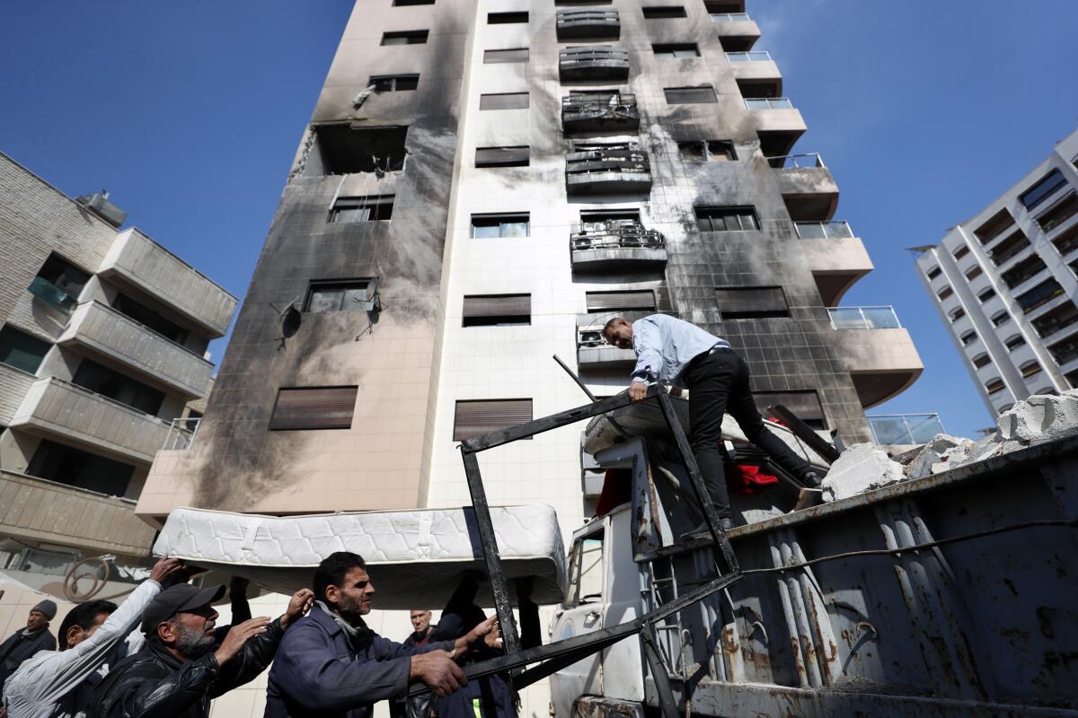 Varias personas retiran los escombros tras un ataque atribuido a Israel en Siria, 