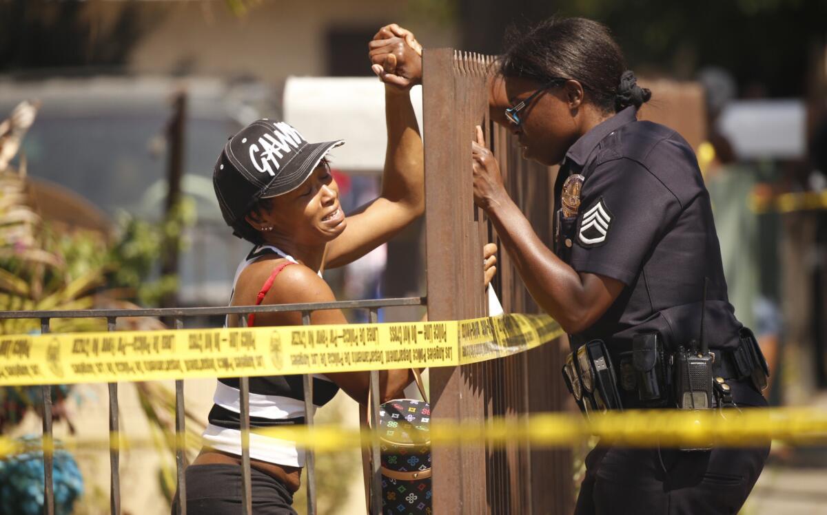 LAPD Sgt. Emada Tingirides, right, comforts the sister of a victim at the scene where two people were fatally shot in South Los Angeles.