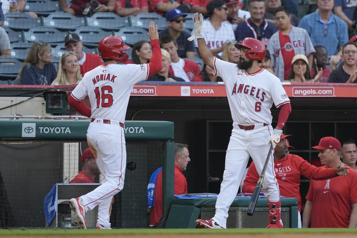 Mickey Moniak (16) high-fives Anthony Rendon on the way back to the Angels dugout after scoring a run
