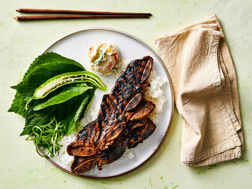 A plate with grilled meat over rice, with sides.