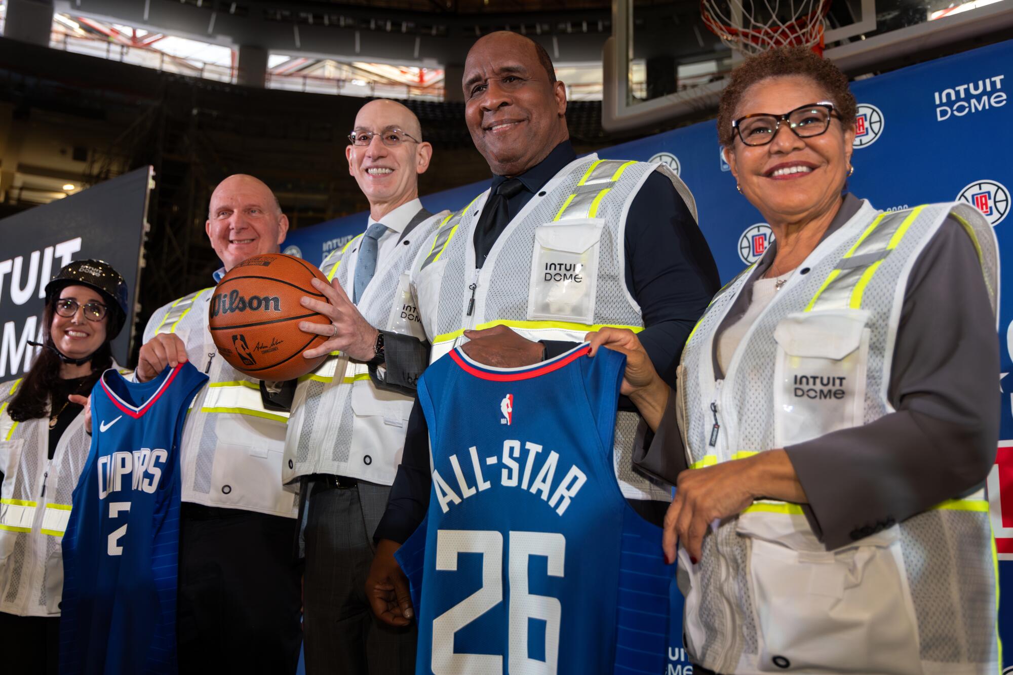 包括 NBA 总裁亚当·萧华（中）在内的政要在 Intuit Dome 举行的新闻发布会上合影留念。