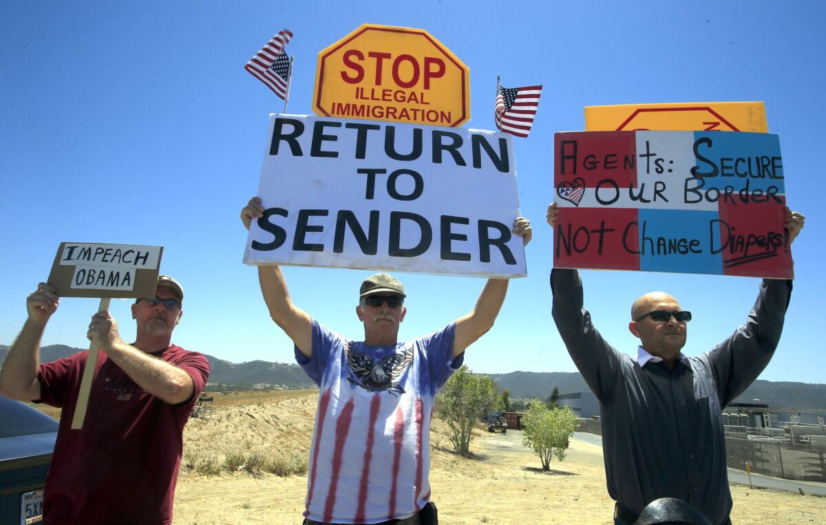 A group of local residents carrying flags and posters assist in turning away three buses carrying immigrant detainees to a Border Patrol station in Murrieta.
