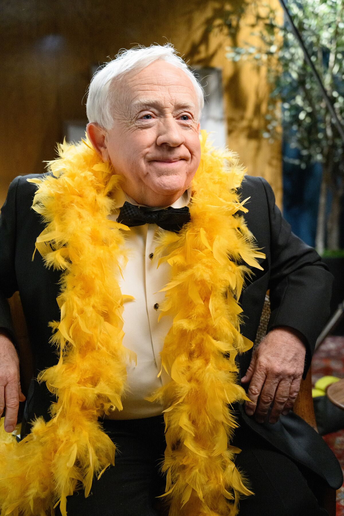 An older man in a tux and a yellow boa.