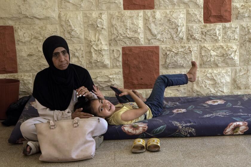 Una mujer desplazada se sienta con su hija en un centro de capacitación vocacional dirigido por la Agencia de las Naciones Unidas para los Refugiados de Palestina en Oriente Medio (UNRWA, por sus siglas en inglés) en la ciudad de Sebline, al sur de Beirut, Líbano, el viernes 4 de octubre de 2024, tras huir de los ataques aéreos israelíes en el sur. (AP Foto/Bilal Hussein)