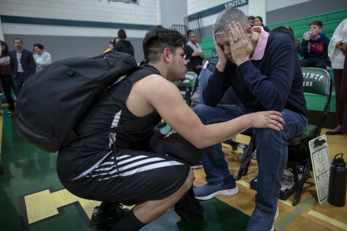 Senior guard Isaac Torres comforts Roybal High School basketball coach Danny O'Fallon moments after losing 73-33 to Providence in the first round of the state championship playoffs.