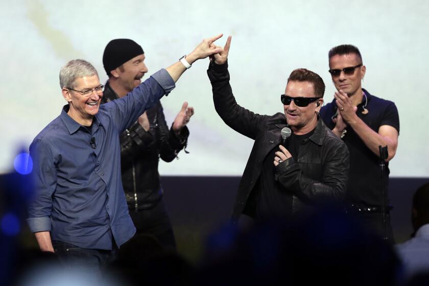 Apple CEO Tim Cook, left, greets Bono from the band U2 after they preformed at the end of the Apple event on Tuesday, Sept. 9, 2014.