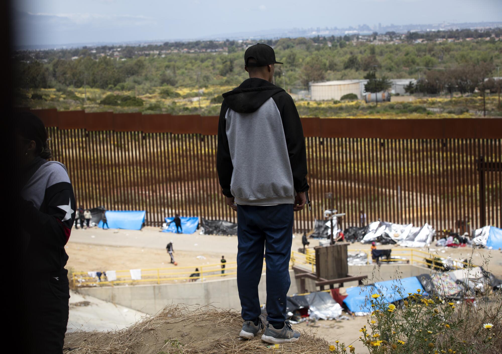 Hundreds of migrants wait between the U.S.-Mexico border walls a day before Title 42 is set to end on Wednesday