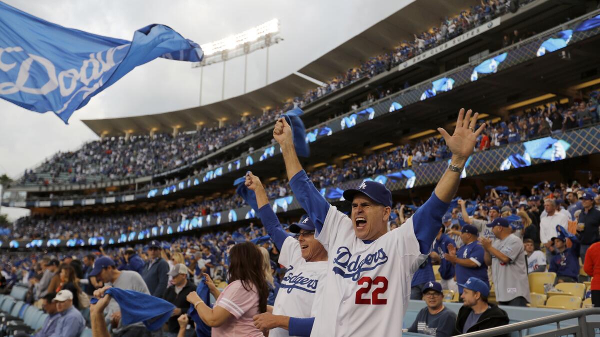 Dodgers fan Tim Kell, right, of Rancho Cucamonga, cheers during Game 2 of the 2017 World Series at Dodger Stadium.