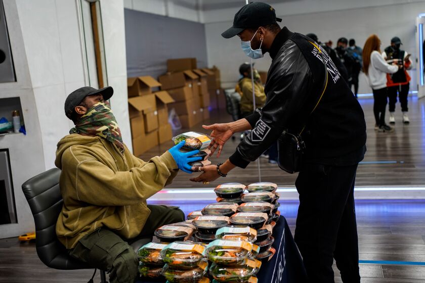 BURBANK, CA - MARCH 25: JaQuel Knight hands meals to Raphael Thomas during a meal giveaway put on by Knight and Everytable at KreativMndz Dance Academy on Wednesday, March 25, 2020 in Burbank, CA. Dancers and creatives impacted by the on-going Coronavirus pandemic were invited to come and pick up meals. (Kent Nishimura / Los Angeles Times)