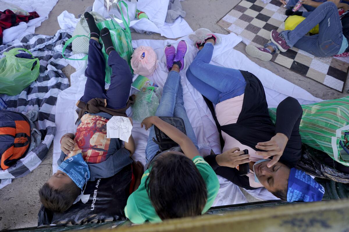 Migrants rest in a gazebo at a park.