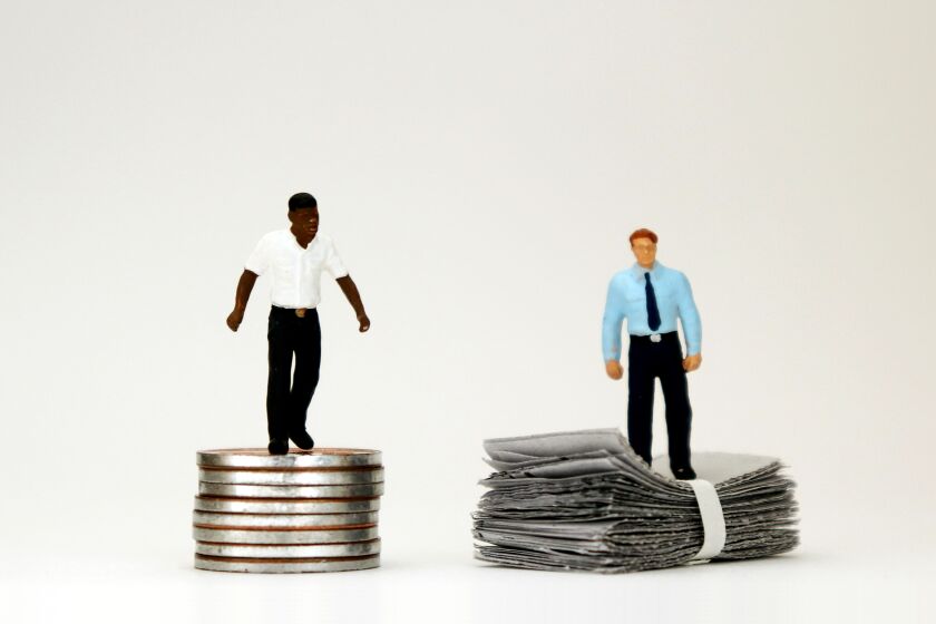 The concept of racial wage discrimination in a company. Money and two miniature men.