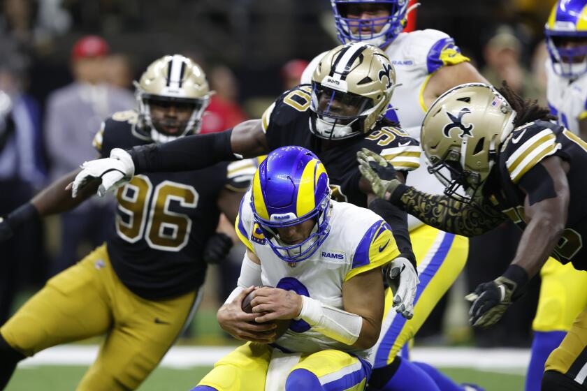 Los Angeles Rams quarterback Matthew Stafford, center, is sacked by New Orleans Saints defenders Tanoh Kpassagnon (90) and Demario Davis, right, in the second half of an NFL football game in New Orleans, Sunday, Nov. 20, 2022. (AP Photo/Butch Dill)