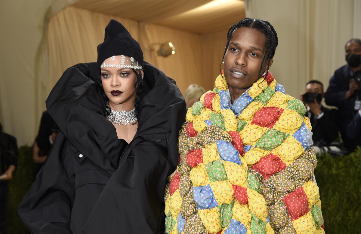 Rihanna poses in a puffy black dress next to ASAP Rocky posing in a rainbow quilt.
