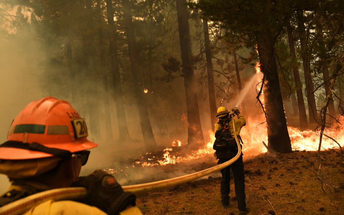 L.A. County firefighter Kevin Reid, right, and Capt. Donald Bailey battle the Caldor fire off Highway 89 west of Lake Tahoe.