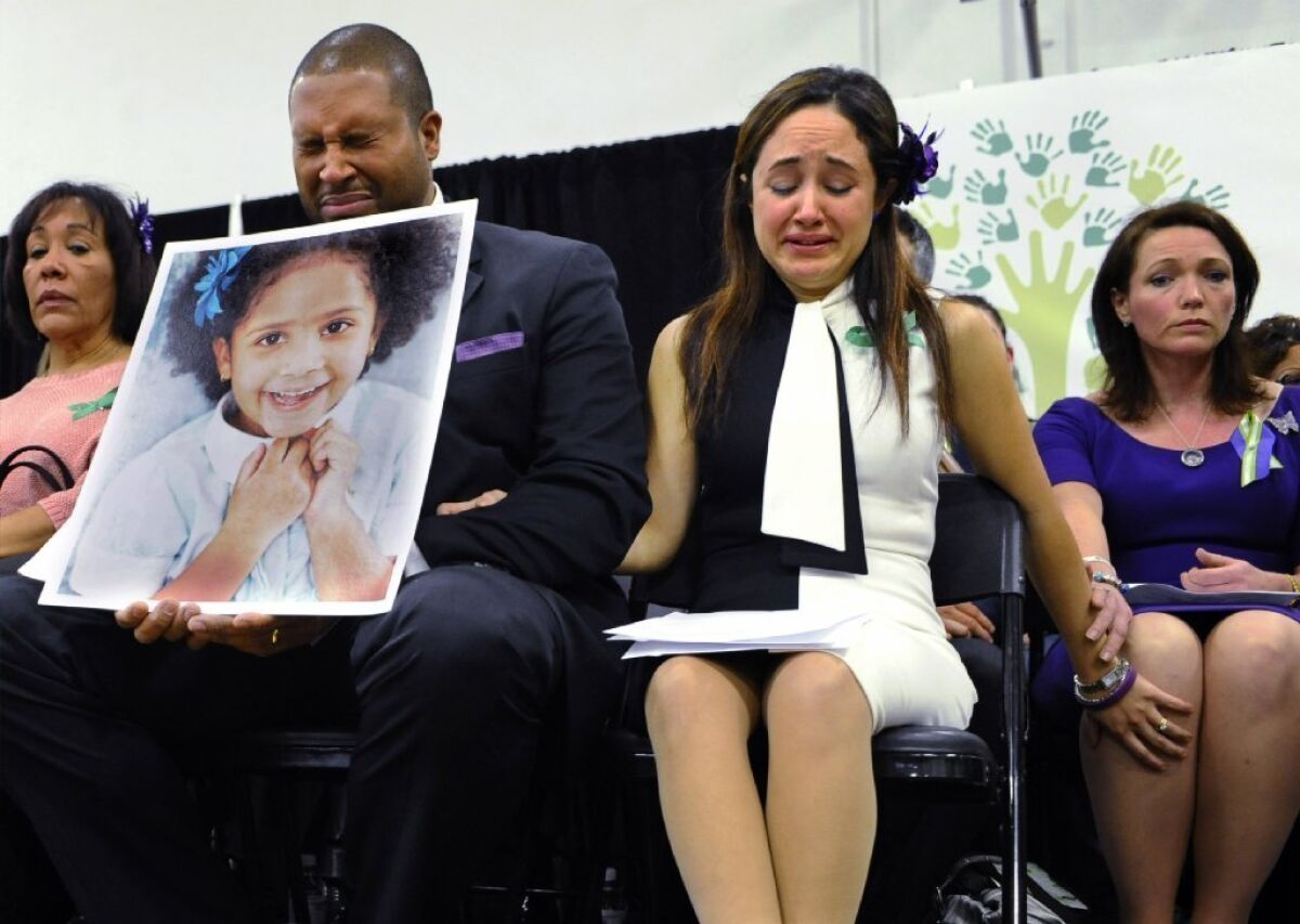 Jimmy Greene, foreground left, and Nelba Marquez-Greene, center, the parents of Sandy Hook Elementary School shooting victim Ana Marquez-Greene, shown in the large photograph; and Nicole Hockley, right, mother of victim Dylan Hockley, react during a news conference at Edmond Town Hall in Newtown, Conn., in January.