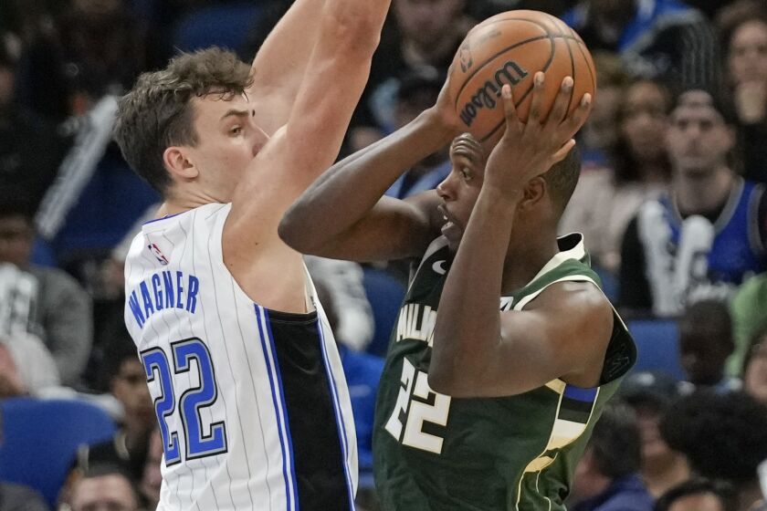 Milwaukee Bucks' Khris Middleton, right, gets off a shot against Orlando Magic's Franz Wagner during the first half of an NBA basketball game, Monday, Dec. 5, 2022, in Orlando, Fla. (AP Photo/John Raoux)