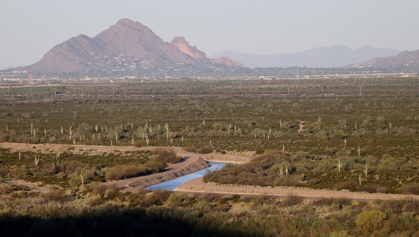 FILE - The Central Arizona Project (CAP) canal cuts through the desert, Friday, March 6, 2015, in Mesa, Ariz. The canal diverts Colorado River water down a 336-mile long system of aqueducts, tunnels, pumping plants and pipelines to the state of Arizona. Arizona, Nevada and California and the U.S.Bureau Of Reclamation will reduce water use by at least 500,000 acre feet in 2022 and again in 2023 in a measure to keep Lake Mead from falling to 1,020 feet. (AP Photo/Matt York, File)