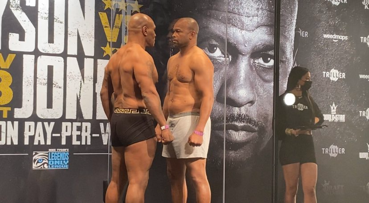 Mike Tyson, left, and Roy Jones Jr. have a staredown while separated by plexiglass after their weigh-in on Friday.