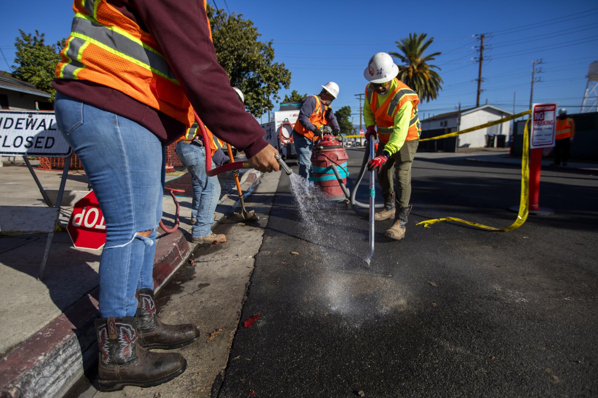 Workers rinse off asphalt.