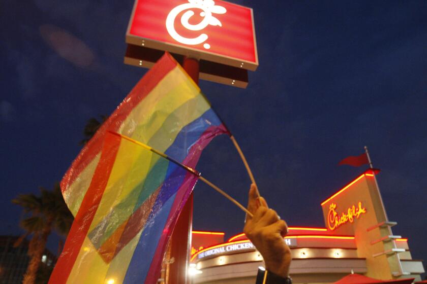 Schaben, Allen J.  B582283589Z.1 LOS ANGELES, CA  AUGUST 3, 2012: Thomas Guastavino, of the Cuddles gay men's choir, holds up gay pride flags while joining a group of gayrights and samesex marriage supporters protesting in front of ChickfilA restaurant in Hollywood Friday, August 3, 2012. LGBT supporters have declared Friday to be National Same Sex Kiss Day and are encouraging others to show up at ChickfilA restaurants nationwide Friday and stage a "kissin." Some activists are combining the "kissins" with Friday evening rallies. (Allen J. Schaben / Los Angeles Times)