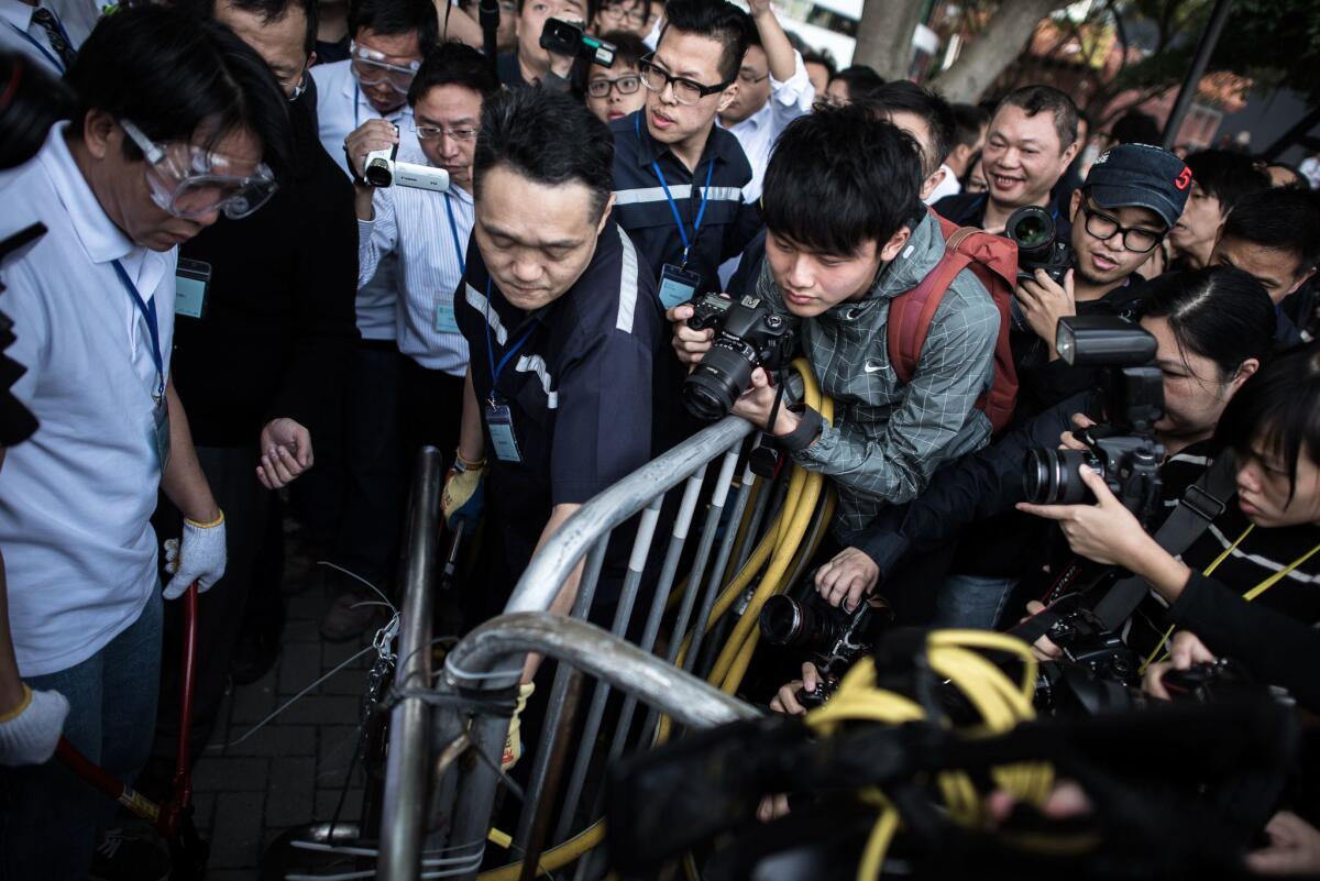 A security staff member, center, removes a barricade outside the Citic Tower at a protest site in the Admiralty district of Hong Kong on Nov 18.