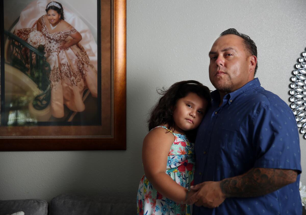 Rafael Saaverdra and daughter Gianna, 5, next to a framed picture of daughter, Gizzelle, 16.