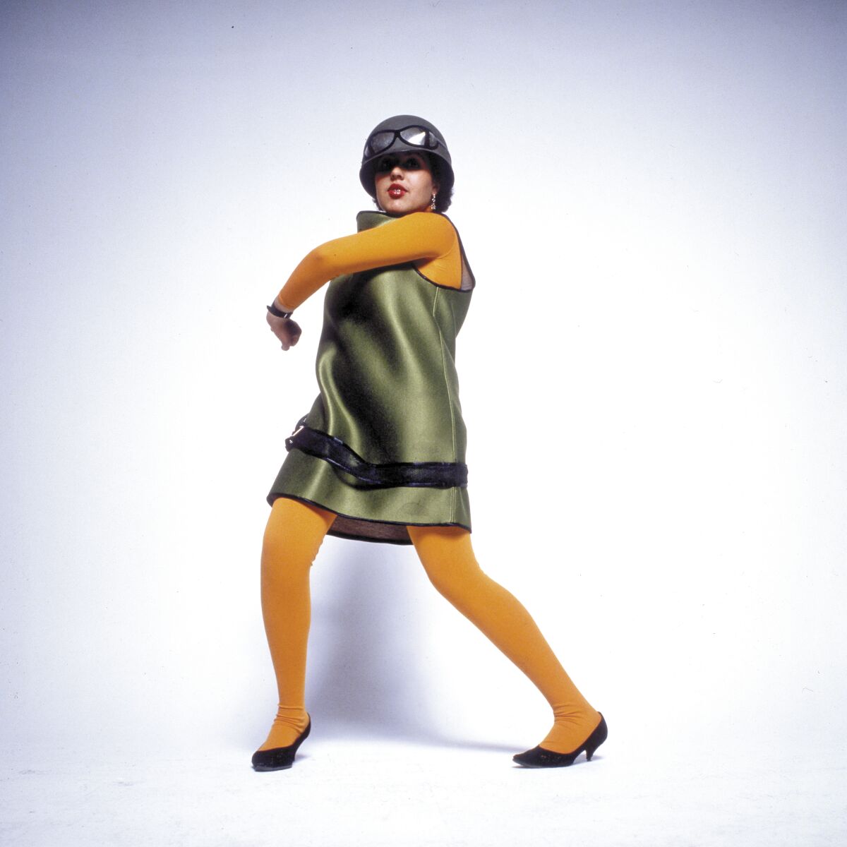 A woman wearing a green dress and a helmet poses for a photo.