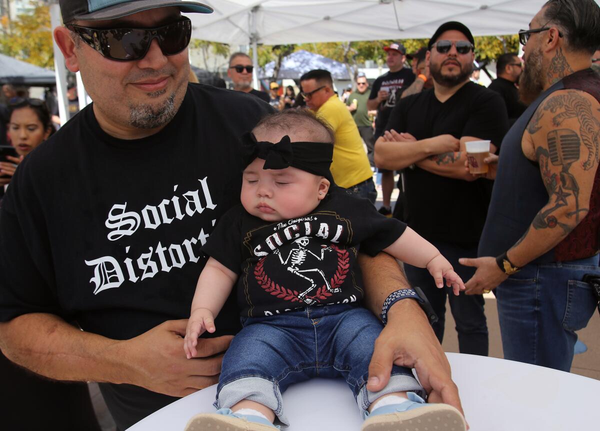 Aaron Cantero, of Fullerton, holds his daughter Olivia, 5 months, both wearing Social Distortion band shirts.