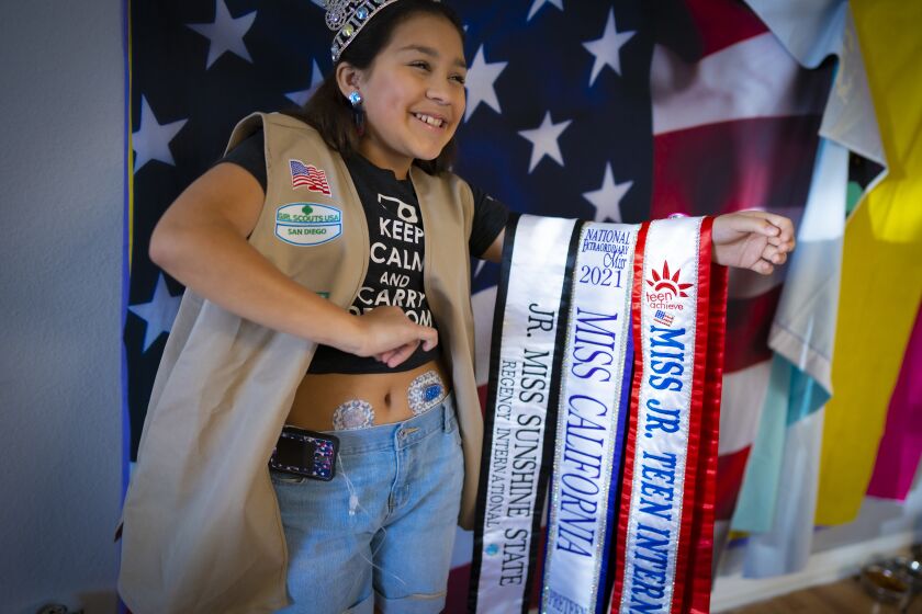Lakeside, CA - March 23: At her home on Wednesday, March 23, 2022 in Lakeside, CA. Bianca Villalobos,12 held her arm holding the three titles she's been honored with. Jr. Teen International, Woman of Achievement / Teen Achieve, Jr. Miss Sunshine State, Regency International, National Extraordinary Miss California Pre Teen. (Nelvin C. Cepeda / The San Diego Union-Tribune)