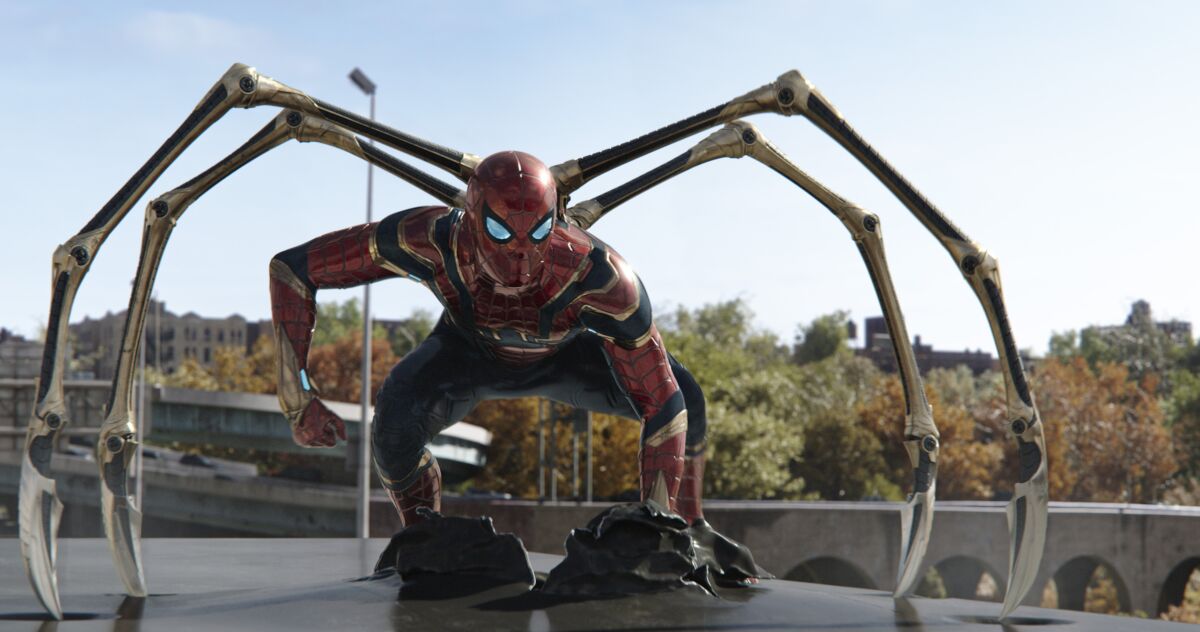 A man crouching in a metallic Spider-Man suit with legs protruding from its back